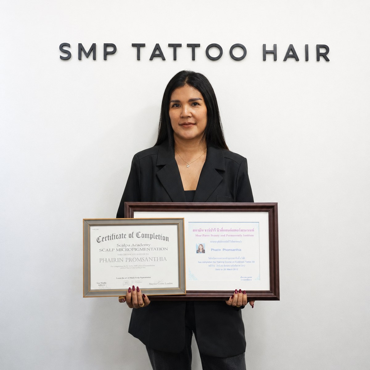 Our lead artist holding her framed training certificates